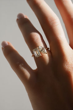 a woman's hand with a diamond ring on top of her finger and the other hand holding an engagement ring