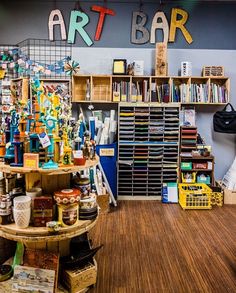 an art bar with lots of items on the shelves and in front of it is a display case full of books