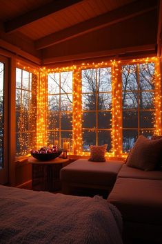 a bedroom with lights on the windows and a couch in front of it at night