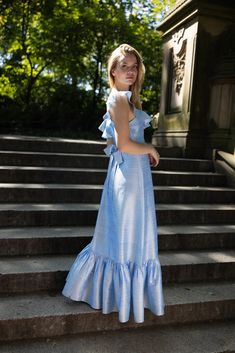 a woman in a blue dress standing on some steps