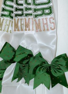 two green and white bows are tied to the side of a t - shirt with sequins on it