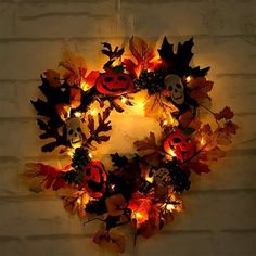 a lighted wreath with pumpkins and leaves