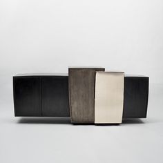 three black and white pieces of furniture sitting on top of each other in front of a gray wall