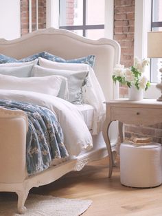 a white bed sitting in a bedroom next to a table with flowers on top of it