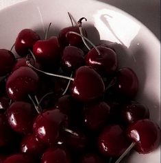 a white bowl filled with cherries on top of a table