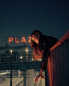 a woman leaning on a rail at night