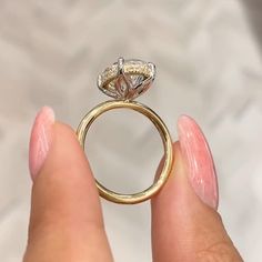 a woman's hand holding a gold ring with a diamond on the top and side