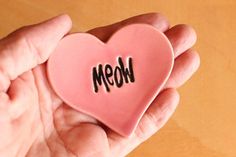 a person holding a pink heart with the word mom written on it in black ink