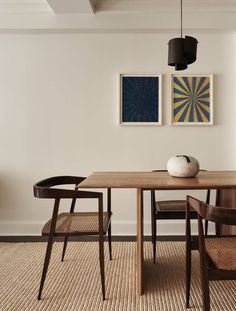 a dining room table with chairs and artwork on the wall