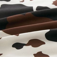 the fabric has brown and black spots on it's white background, as well as an animal - print pattern