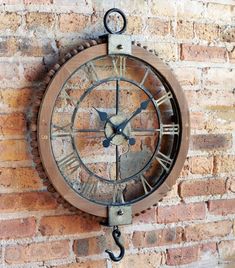 a clock mounted to the side of a brick wall next to a hook on a chain