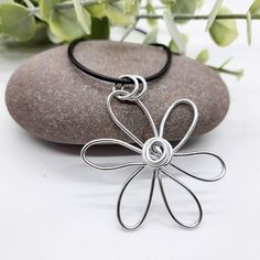 a silver flower pendant sitting on top of a rock