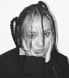 a black and white photo of a woman with braids on her hair looking at the camera