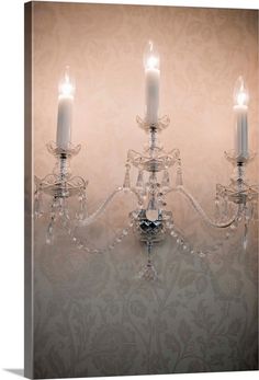 a chandelier with three lit candles hanging from it's sides, in front of a wallpapered background