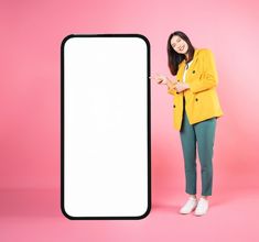 a woman standing next to an empty white sign on a pink background with her hands in the air