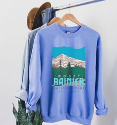 Mount Rainier National Park Sweatshirt, National Park Shirt, Vintage Retro WPA Graphic Camp Sweater Gift Printed on a classic unisex Gildan cotton sweatshirt. Colors: Carolina Blue *50% Cotton 50% Polyester *Medium-heavy fabric * Loose fit *Runs pretty true to size, slightly larger ♥♥SIZING♥♥ ♥Modern Unisex Fit. Women may want to size down if you prefer a more fitted look. Men may want to size up if you want a looser fitting shirt. SHIPPING TIMES ♥It takes us about 1-7 days to create your item. Fall Hiking Sweatshirt With Letter Print, Casual Hiking Sweatshirt With Letter Print, Sporty Crew Neck Sweatshirt For Hiking, Casual Letter Print Sweatshirt For Hiking, Outdoor Blue Sweatshirt With Letter Print, Winter Casual T-shirt For Outdoor Activities, Casual Winter T-shirt For Outdoor Activities, Outdoor Crew Sweatshirt With Letter Print, Outdoor Crew Sweatshirt With Graphic Print