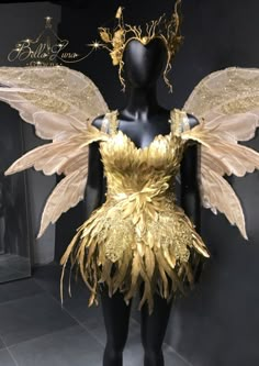 a mannequin dressed in gold and white with wings on it's head