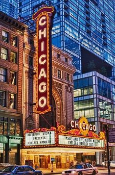 the chicago theater marquee is lit up at night in front of tall buildings