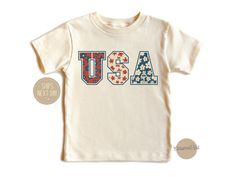 Celebrate American pride with our patriotic USA toddler shirt, perfect for little ones ready to show their love for the red, white, and blue! This charming shirt features bold USA lettering, making it ideal for Fourth of July festivities and year-round patriotism. Crafted from premium, soft fabric, it ensures comfort and style for your little American. How to order: Please select size & style from the drop down menu, select quantity If there is personalization box available(for certain listings) Patriotic Pre-shrunk Shirt For 4th Of July, Cute Cotton T-shirt For 4th Of July, 4th Of July Name Print Short Sleeve T-shirt, 4th Of July Short Sleeve T-shirt With Name Print, White Shirt Made In Usa For 4th Of July, Cute Short Sleeve Shirt For 4th Of July, Cute American Flag Print Short Sleeve T-shirt, 4th Of July Short Sleeve Tops With Name Print, Cute Cotton Independence Day Top