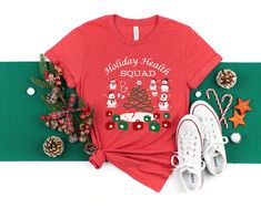 Premium quality, custom made to order Holiday Health Squad Shirt for the Health Office Team. Cute Snowman shirt for any health office or medical clinic team. Perfect Holiday T-Shirt for all the health staff! 1) Select your choice of shirt color:  -White -Soft Cream -Athletic Heather (Light Grey) -Baby Blue -Kelly Green -Heather Red Note: Shirt colors come with font colors as pictured in images. 2) Select your size & add to cart 3) If purchasing more than one shirt, you will need to return to thi Medical Office Holiday Shirt, Health Unit Coordinator Shirts, Christmas Shirt For Doctor Office, Medical Christmas Shirts, Funny Christmas Nurse Shirts, School Nurse Office Decorations, Nurse Team, Unisex Looks, Snowman Shirt