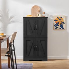 a black cabinet sitting in the corner of a room next to a table and chairs