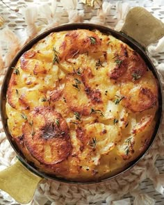 a casserole dish with cheese and herbs in a bowl on a wicker tablecloth