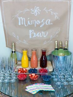 a table topped with glasses filled with fruit and drinks next to a sign that says mimosa bar