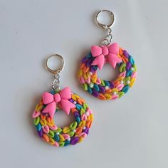 two colorful earrings with bows on them sitting next to each other in front of a white background