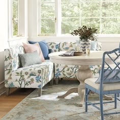 a living room filled with furniture and a white table surrounded by blue chairs, pillows and rugs