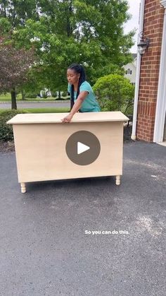 a woman standing in front of a wooden box on the ground with her hand on top of it