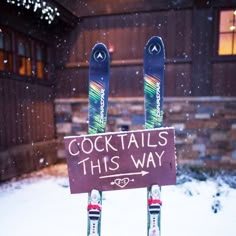 two skis sticking out of the back of a sign that says cocktails this way