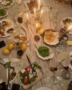 the table is set with many plates and silverware, candles, and food on it