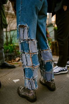 two people wearing jeans with chains attached to the legs and ankles, standing next to each other