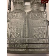 two empty glass bottles sitting on top of a metal shelf