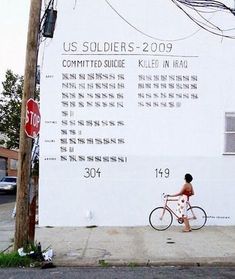 a person on a bike in front of a building with a us soldier's sign