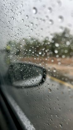 rain drops on the windshield of a car as it drives down a road in the rain