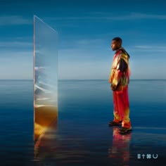 a man standing in front of a large glass block on top of a body of water