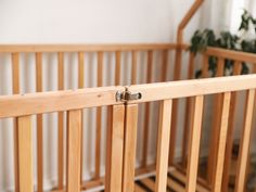 a wooden crib with a plant in the corner and a door handle on it