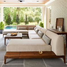 a living room filled with furniture next to a swimming pool on top of a stone floor