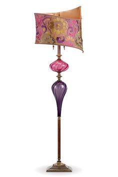 a purple lamp with a pink shade on top and a gold base, sitting on a white background