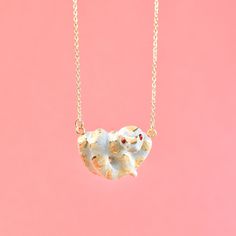 a small white elephant necklace on a gold filled chain against a pink background with the word love written in it