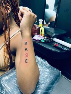 a woman with braids on her arm has a tattoo that reads rare