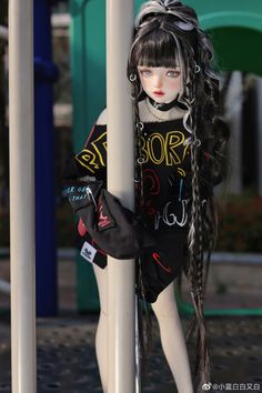 a doll with long hair leaning against a pole