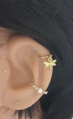 a close up view of a person's ear with dragonfly earrings on it