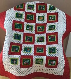 a red and white quilted blanket on top of a wooden floor next to a wall