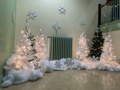 three white christmas trees with snowflakes on them in front of a radiator