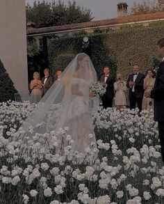 a bride and groom are walking through the flowers in front of their wedding ceremony guests