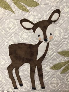 a close up of a quilt with a deer on it's face and leaves in the background