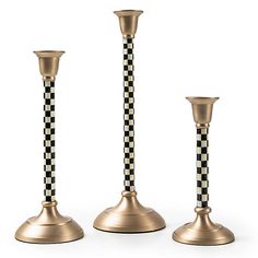 three gold candlesticks with checkerboard design on the top, one black and white