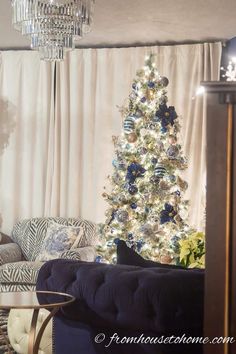 a living room with a christmas tree and couches in front of the window,